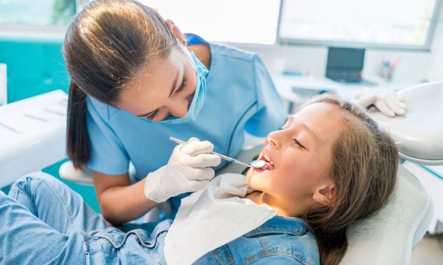 Young girl sitting on dental chair getting her teeth checked by a dentist