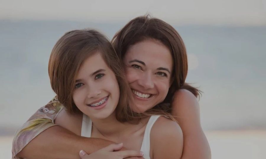 Mother hugging teenage daughter with braces