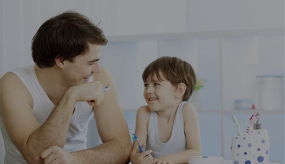 Father teaching young son proper oral health care