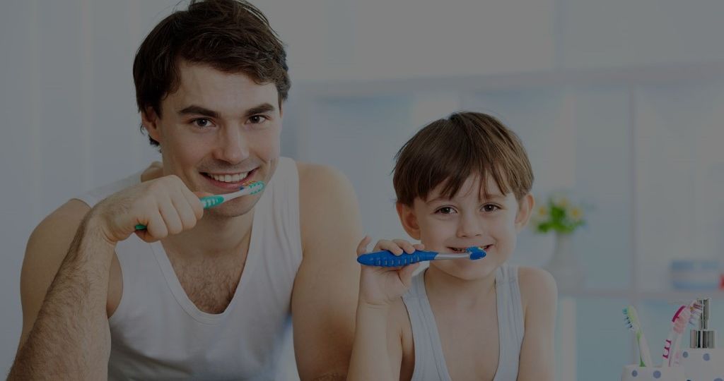 Father and son smiling and brushing teeth together