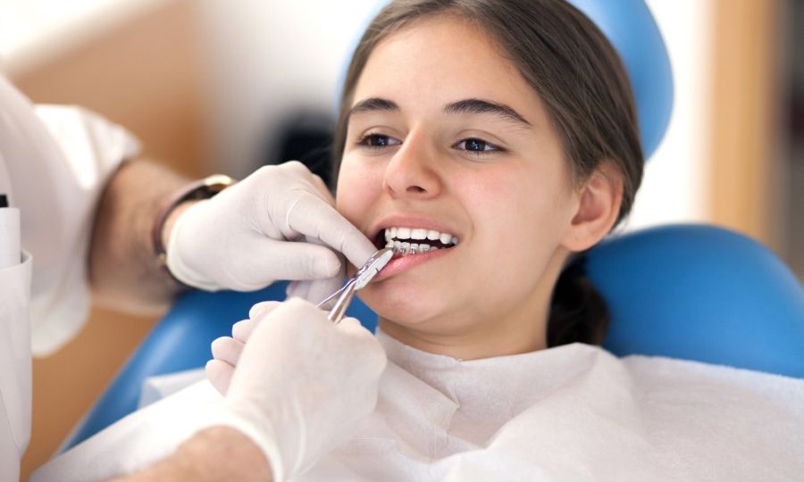 Young teen patient getting braces adjusted by an orthodontist