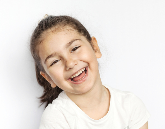 Little girl in ponytail smiling and showing healthy baby teeth(2)